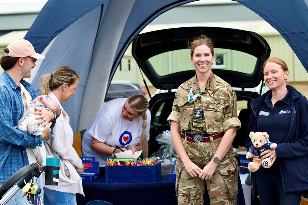 Group Captain Louise Henton with a family, standing at the RAF Benevolent Fund stall.